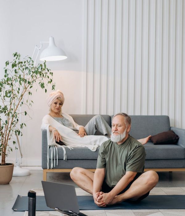 A person happily starting their yoga journey on a mat in a comfortable living room.